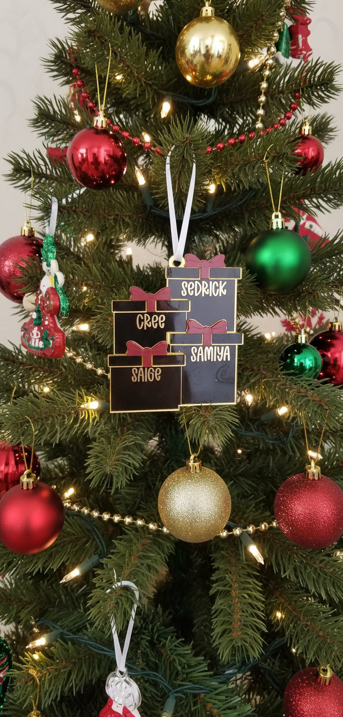 Two gold and black Christmas tree ornaments with red ribbons on a frosted branch background.